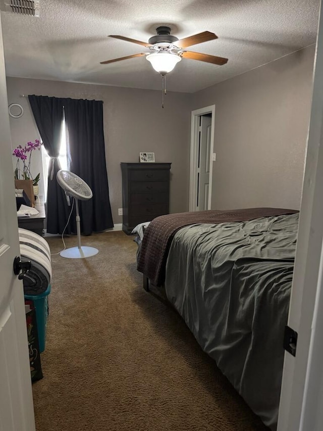 carpeted bedroom featuring visible vents, a textured ceiling, and ceiling fan