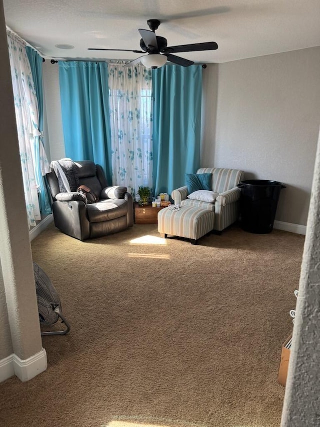 living area with carpet flooring, baseboards, and a ceiling fan