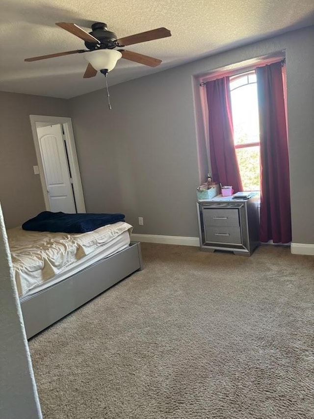 bedroom with ceiling fan, a textured ceiling, baseboards, and carpet floors