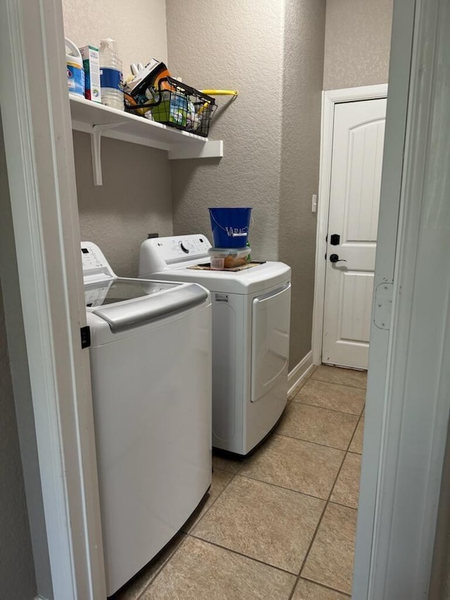 laundry area featuring light tile patterned floors, laundry area, washing machine and dryer, and a textured wall