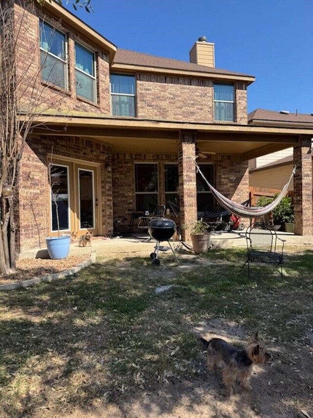 back of house featuring a patio area, brick siding, and a chimney