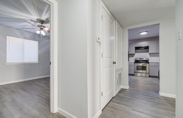 corridor with light wood-style flooring, visible vents, and baseboards