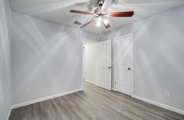 unfurnished bedroom featuring visible vents, a ceiling fan, baseboards, and wood finished floors