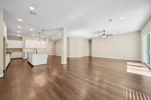 unfurnished living room with a sink, visible vents, a ceiling fan, and dark wood-style flooring