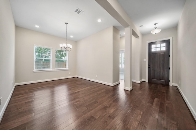 foyer with a wealth of natural light, visible vents, dark wood-style floors, and a chandelier