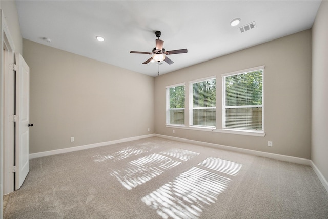 spare room featuring visible vents, light colored carpet, baseboards, and ceiling fan