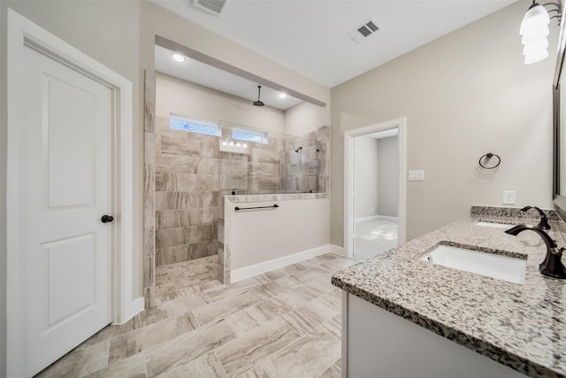 bathroom featuring baseboards, visible vents, double vanity, a sink, and walk in shower