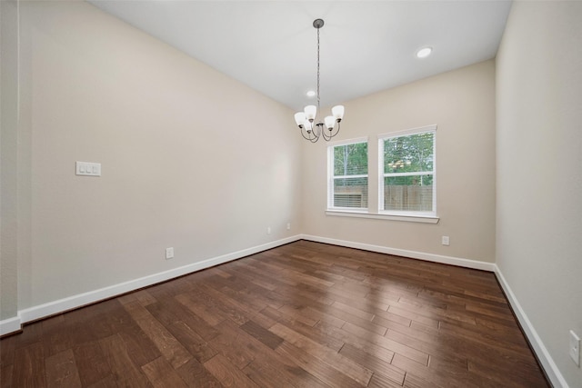 spare room featuring baseboards, an inviting chandelier, and dark wood-style flooring