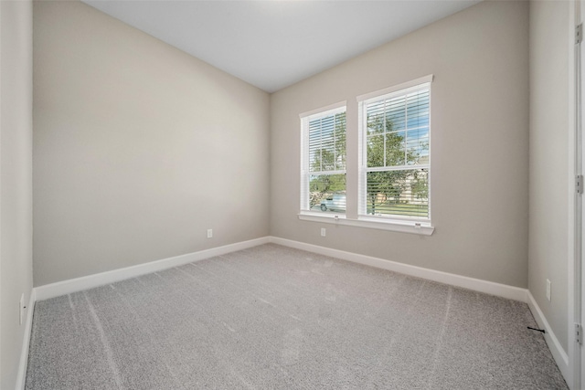 unfurnished room featuring light colored carpet and baseboards