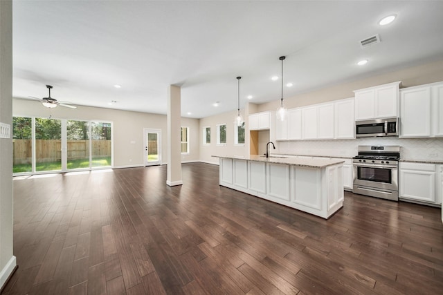 kitchen featuring visible vents, a sink, tasteful backsplash, open floor plan, and appliances with stainless steel finishes