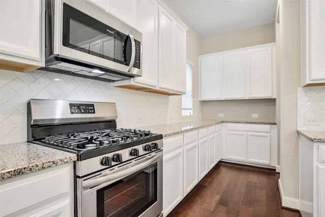 kitchen with light stone counters, backsplash, dark wood finished floors, stainless steel appliances, and white cabinets