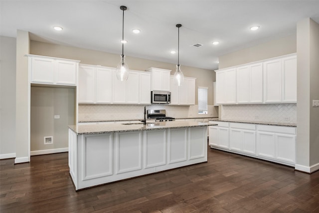 kitchen with a kitchen island with sink, a sink, dark wood-type flooring, white cabinets, and appliances with stainless steel finishes