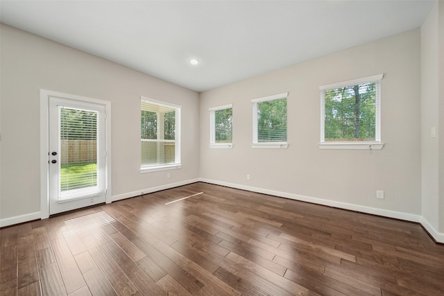 unfurnished room with recessed lighting, baseboards, dark wood-type flooring, and a healthy amount of sunlight