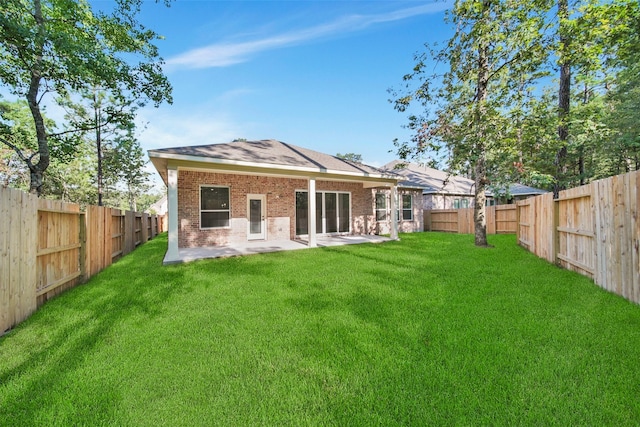 back of house featuring a patio area, a lawn, brick siding, and a fenced backyard