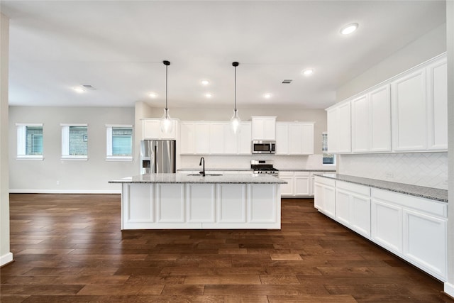 32193 Park Plains Dr, Conroe, TX 77385 - kitchen featuring stainless steel appliances, tasteful backsplash, white cabinets, a center island with sink, and light stone counters