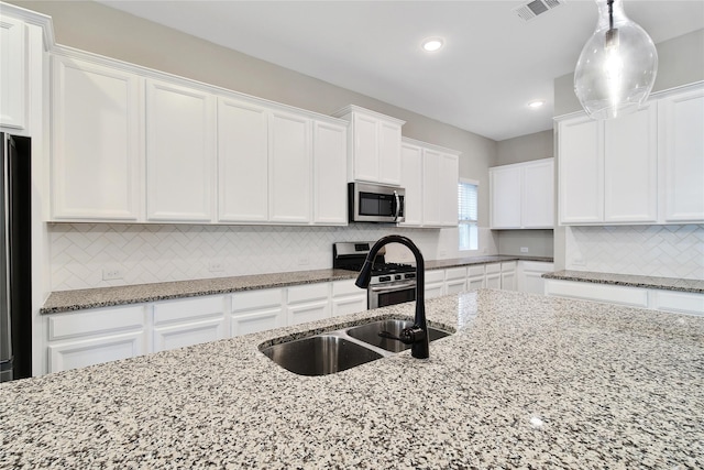 32193 Park Plains Dr, Conroe, TX 77385 - kitchen with appliances with stainless steel finishes, a sink, white cabinetry, tasteful backsplash, and recessed lighting
