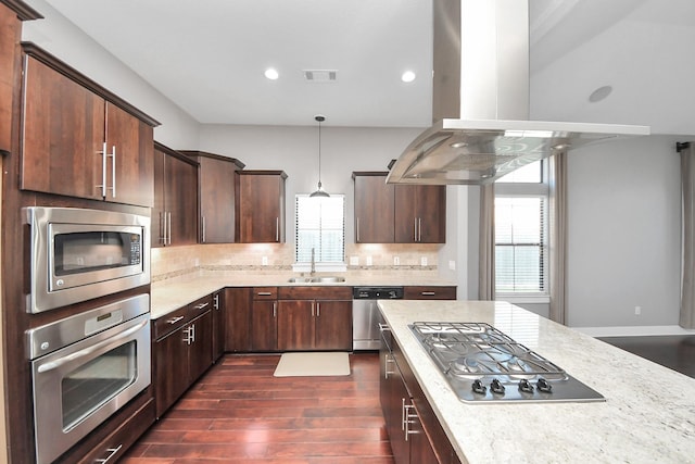 kitchen with visible vents, island exhaust hood, a sink, tasteful backsplash, and appliances with stainless steel finishes