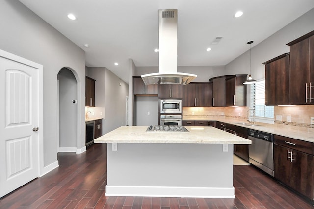 kitchen featuring island exhaust hood, a sink, backsplash, dark brown cabinetry, and appliances with stainless steel finishes