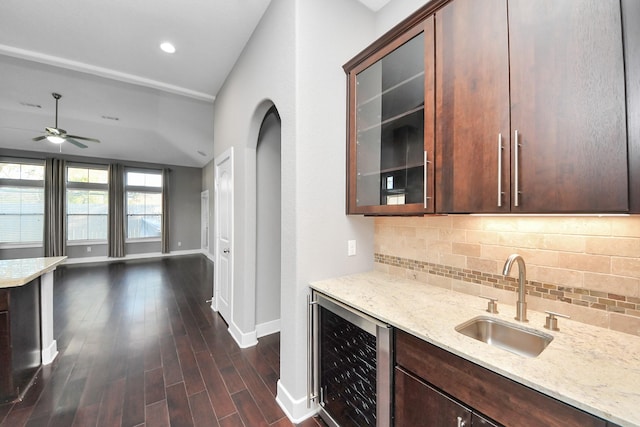 kitchen with light stone counters, dark wood finished floors, a sink, decorative backsplash, and wine cooler