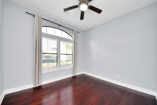 spare room with dark wood-style floors, visible vents, ceiling fan, and baseboards