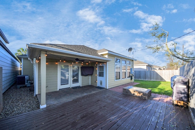 deck featuring fence, a lawn, cooling unit, french doors, and a ceiling fan