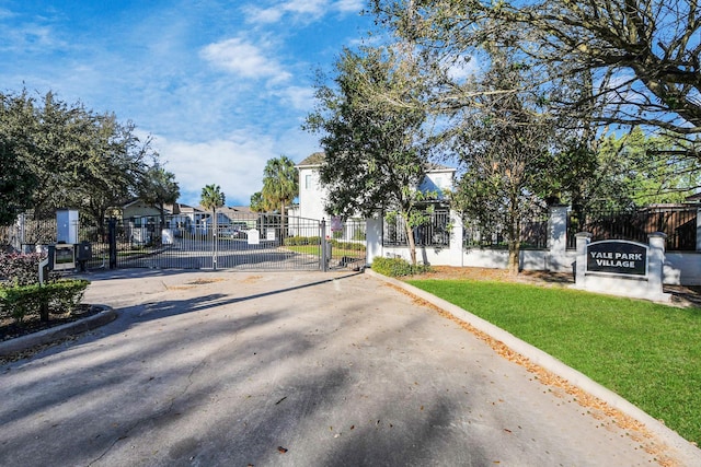 view of street with a gate, curbs, a residential view, and a gated entry