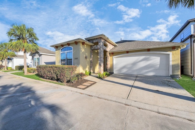 view of front of property featuring stone siding, stucco siding, an attached garage, and concrete driveway