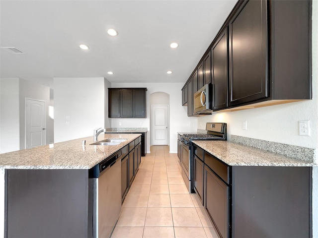 kitchen with light stone counters, light tile patterned floors, recessed lighting, appliances with stainless steel finishes, and a sink