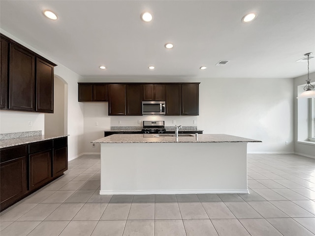 kitchen featuring visible vents, a sink, stainless steel appliances, arched walkways, and light stone countertops