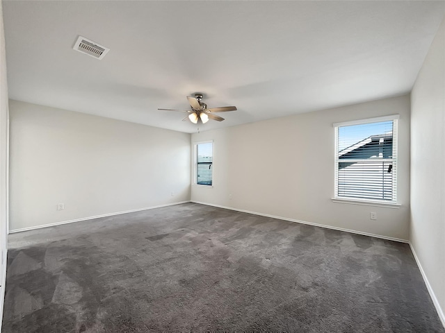 unfurnished room with plenty of natural light, a ceiling fan, visible vents, and dark colored carpet