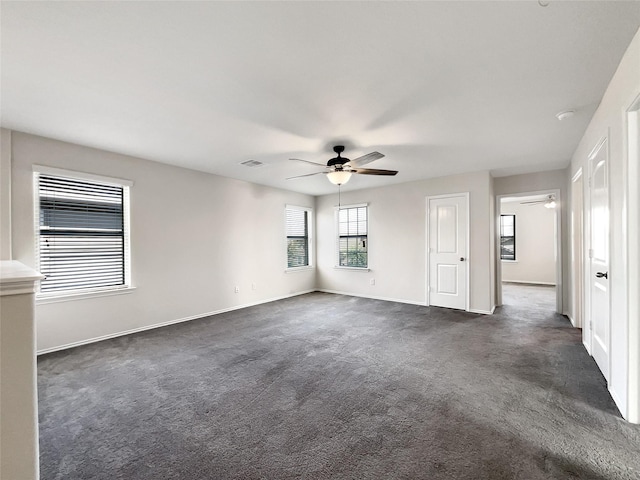 empty room with baseboards, ceiling fan, and dark colored carpet