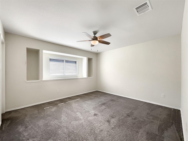 spare room with visible vents, baseboards, ceiling fan, and dark colored carpet