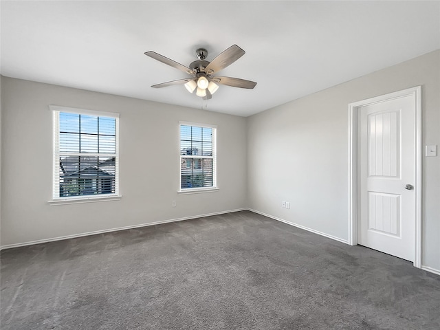 spare room with dark colored carpet, baseboards, and a ceiling fan