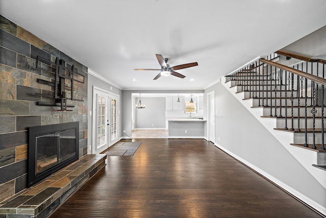 unfurnished living room with a tile fireplace, stairs, baseboards, and wood finished floors