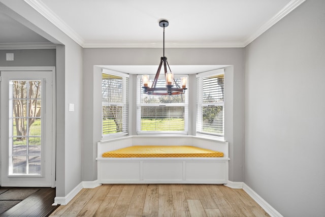 unfurnished dining area with crown molding, a notable chandelier, baseboards, and light wood finished floors