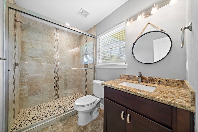 bathroom featuring visible vents, a shower stall, toilet, and vanity