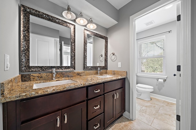 full bathroom featuring double vanity, toilet, baseboards, and a sink