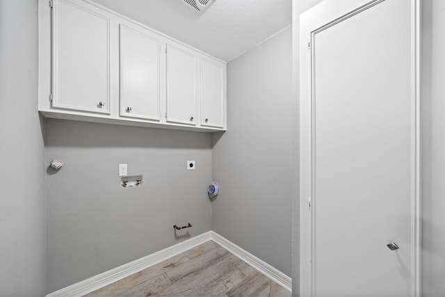 washroom with baseboards, light wood-type flooring, washer hookup, hookup for a gas dryer, and cabinet space