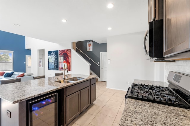 kitchen with gas stove, beverage cooler, light stone countertops, a sink, and open floor plan