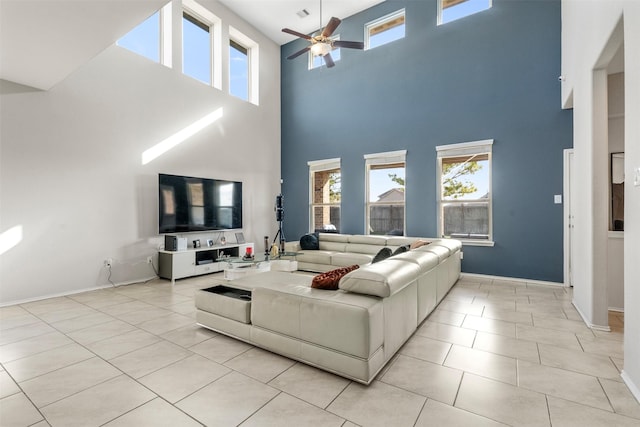 living area with light tile patterned floors, baseboards, and ceiling fan