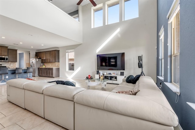 living room with a high ceiling, light tile patterned floors, recessed lighting, and ceiling fan