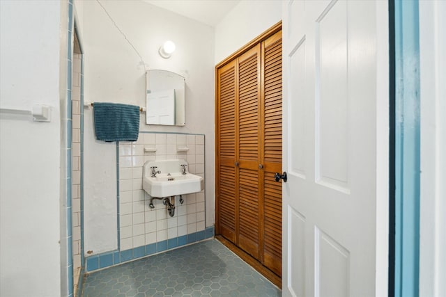 bathroom featuring tile patterned floors, tile walls, and a sink