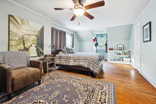 bedroom with crown molding, lofted ceiling, wood finished floors, a textured ceiling, and a ceiling fan