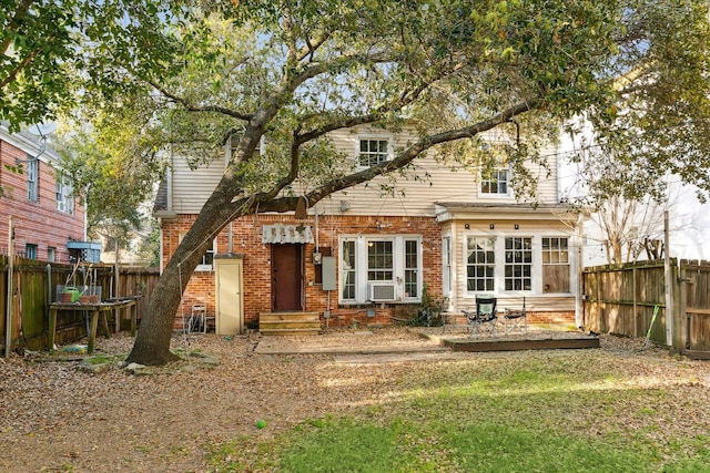 back of house featuring brick siding and fence