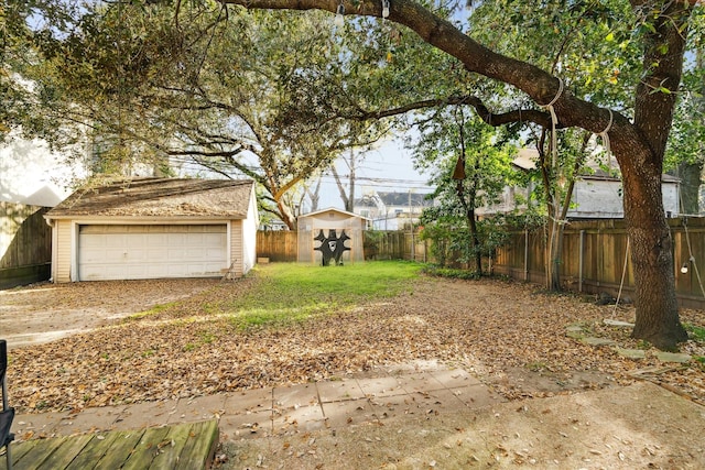 view of yard with an outbuilding, a fenced backyard, and a detached garage