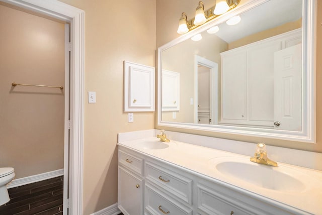 full bath featuring double vanity, toilet, baseboards, and a sink