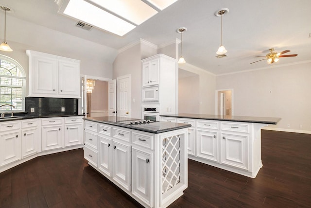 kitchen featuring dark countertops, visible vents, a center island, white cabinets, and white appliances