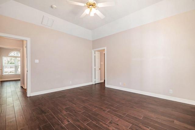 spare room featuring dark wood-type flooring, a ceiling fan, and baseboards