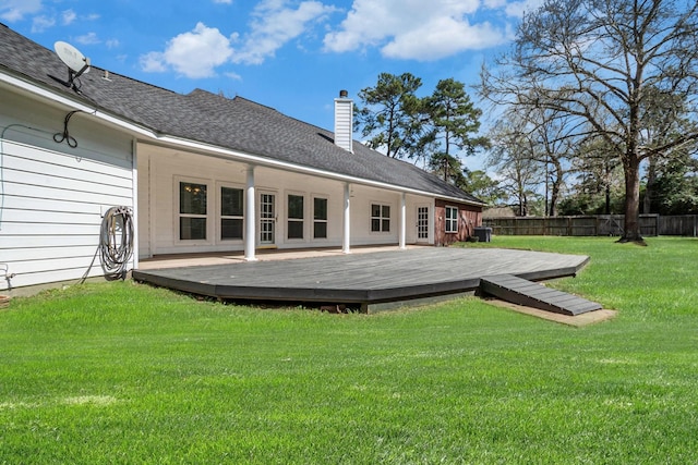 rear view of property featuring a wooden deck, a lawn, a chimney, and fence