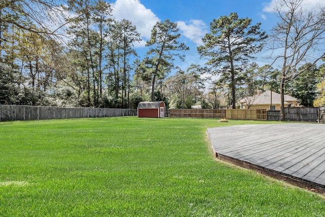 view of yard with an outbuilding, a deck, a shed, and a fenced backyard